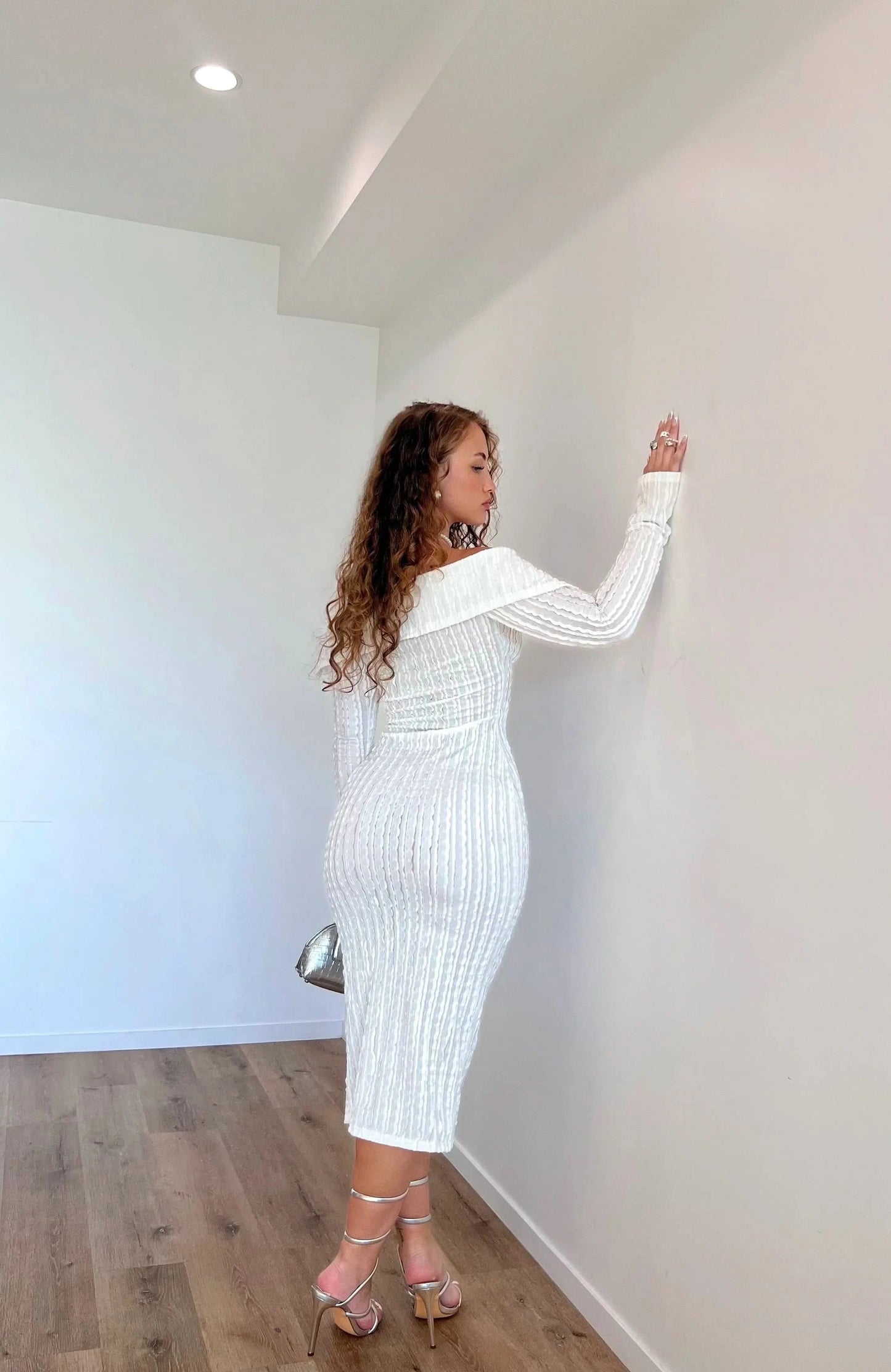 Back view of white off-shoulder ribbed dress showing fitted silhouette