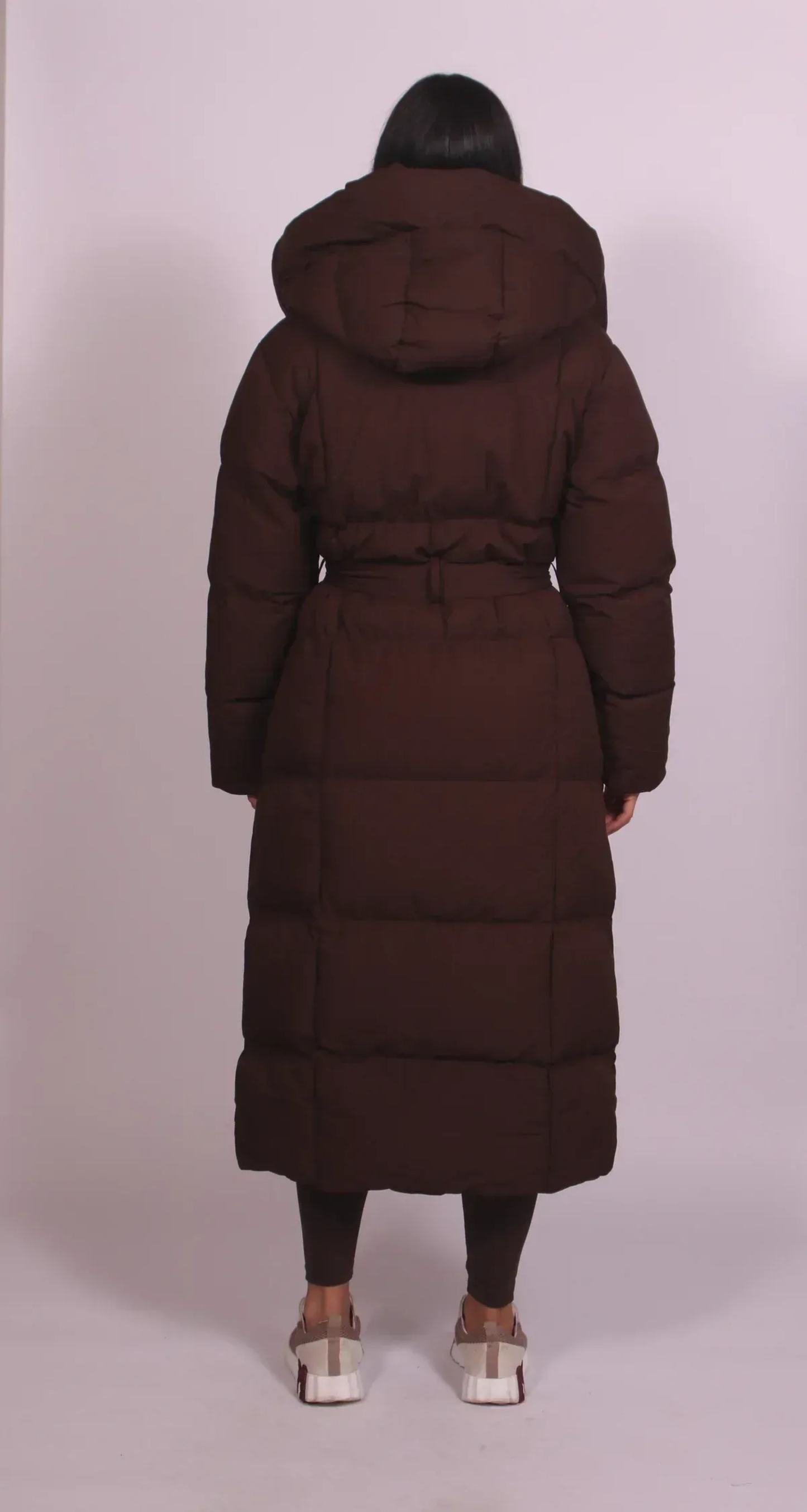 Back view of chocolate brown maxi puffer coat showing quilted seams and hooded design