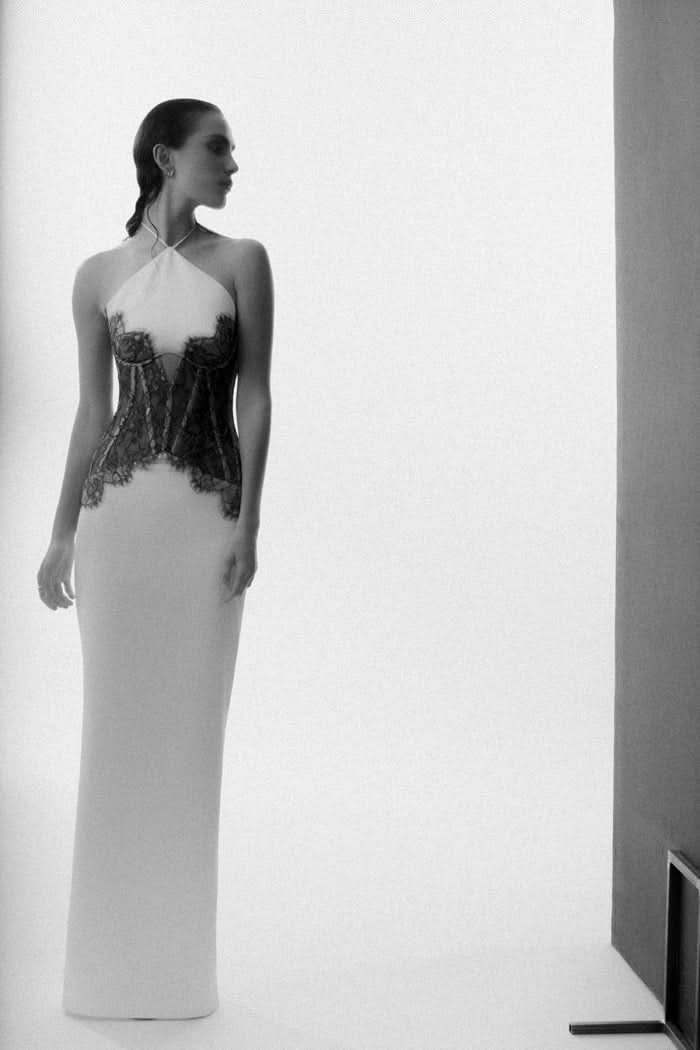 Three-quarter view of white maxi dress with black lace bodice and halter neckline