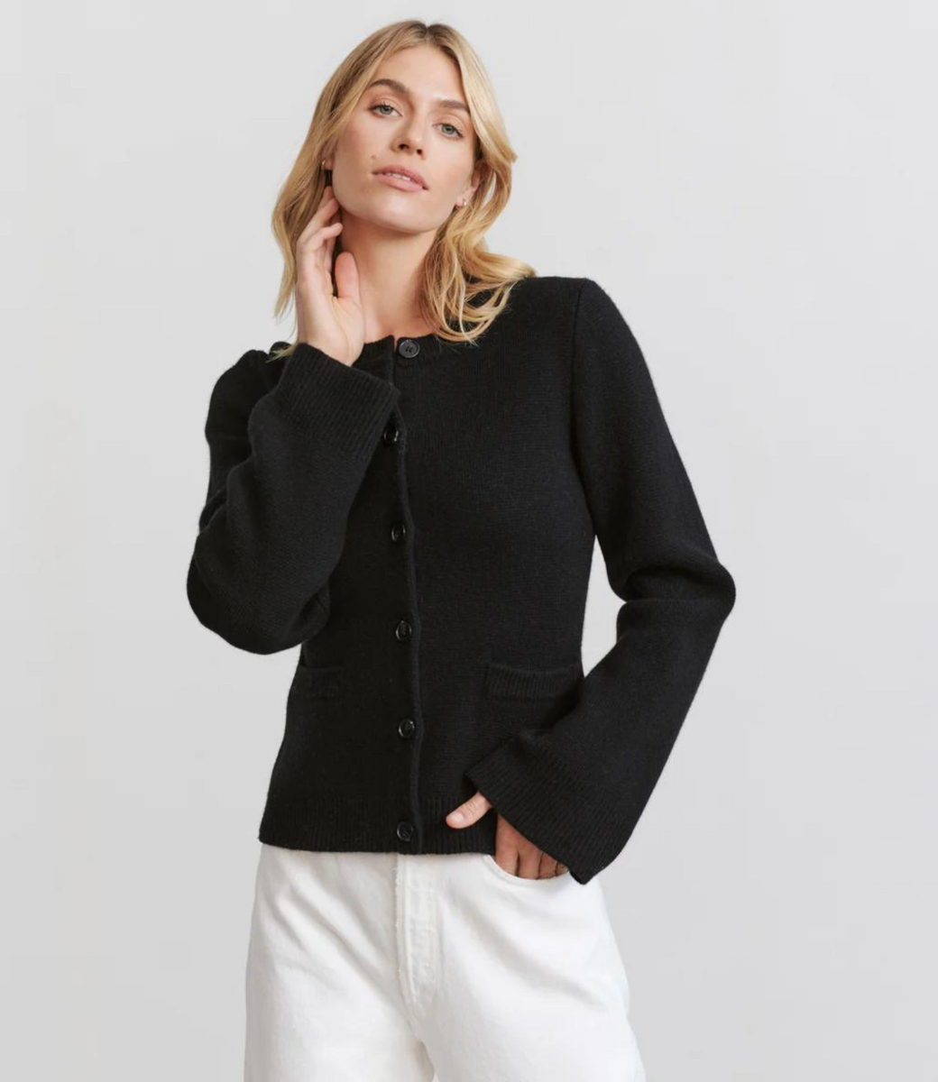Taupe knit cardigan with button front and ribbed hem, side view with white pleated skirt