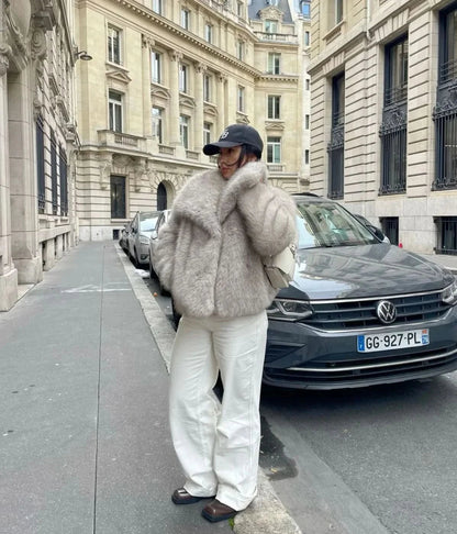 Cream fur coat with oversized collar worn with white pants and black cap