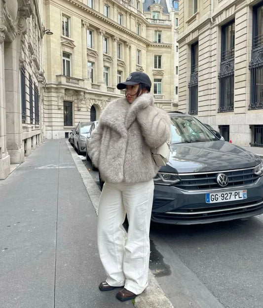 Cream fur coat with oversized collar worn with white pants and black cap