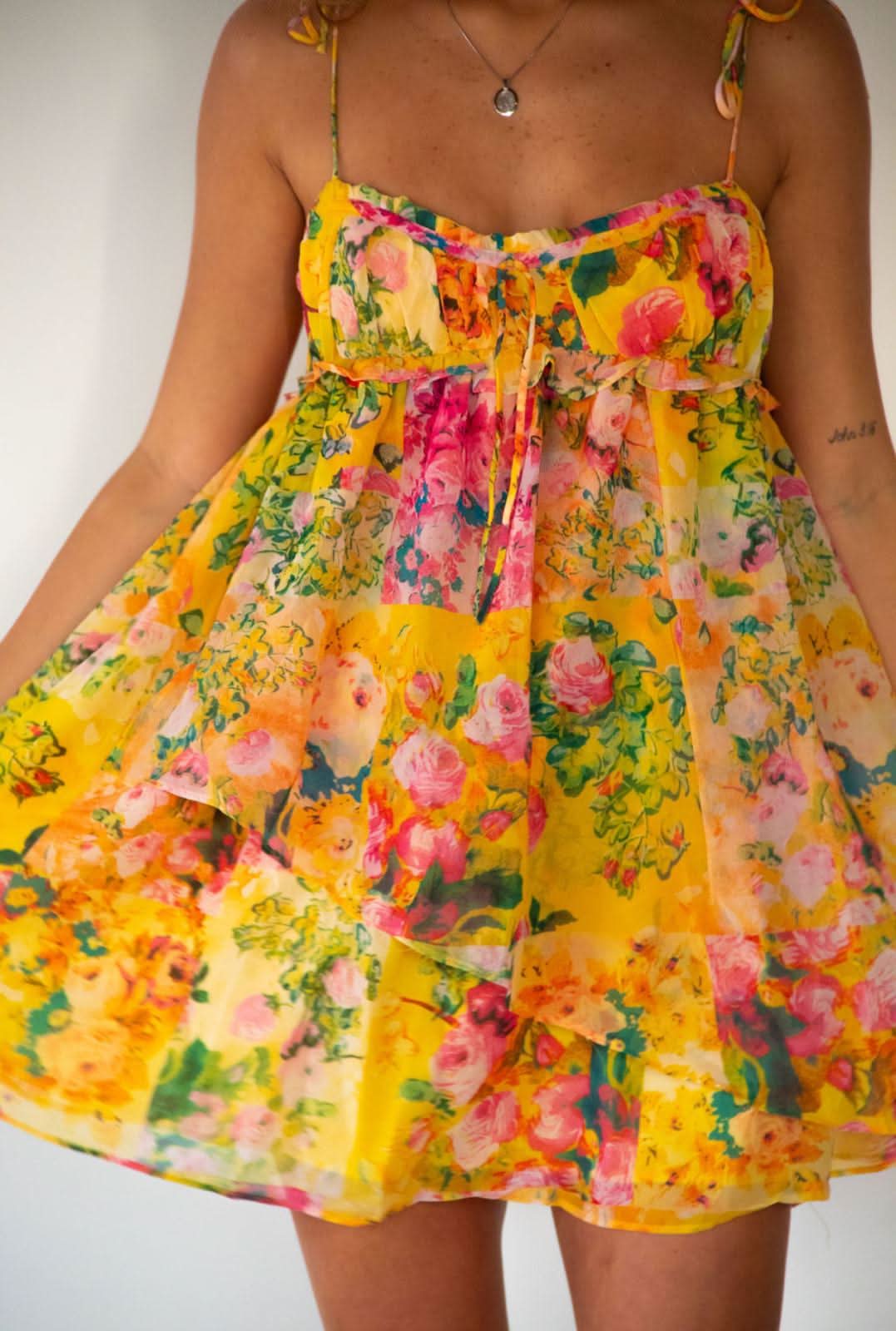 Close-up of yellow floral mini dress bodice with sweetheart neckline and gathered waist