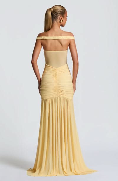 Back view of pale yellow maxi dress with off-shoulder cut and pleated skirt