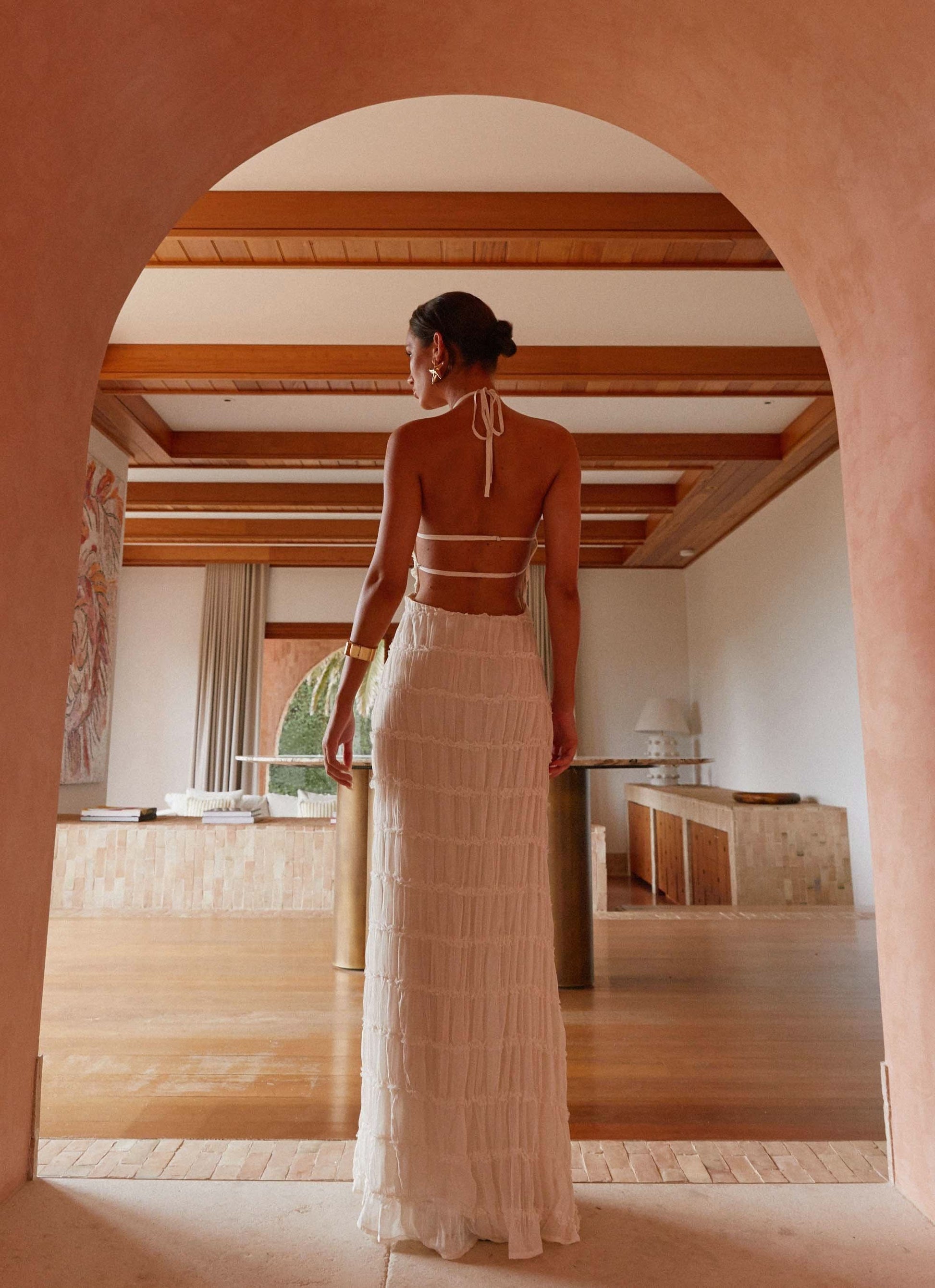 Cream pleated halter maxi dress back view in architectural setting
