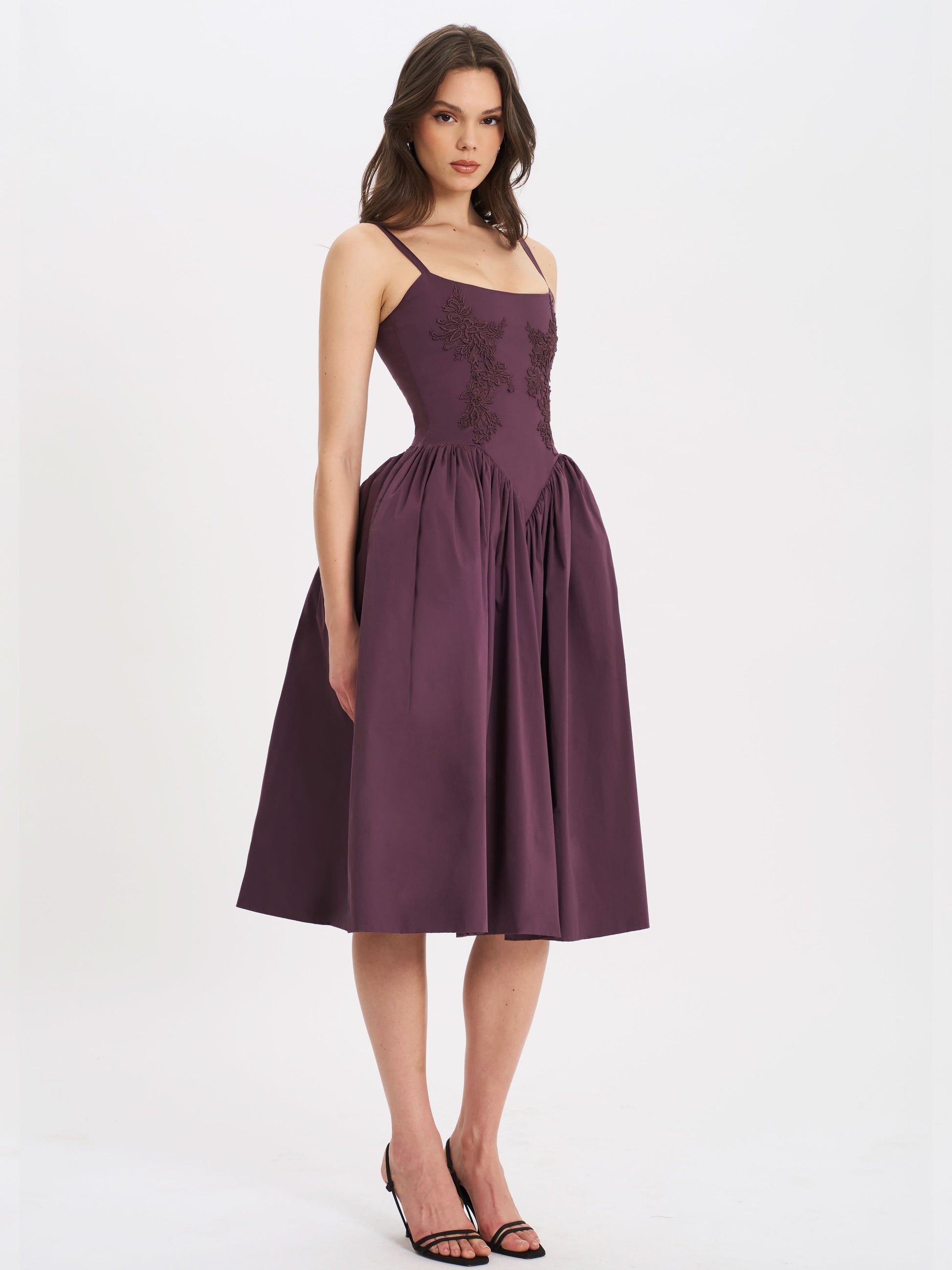 Purple midi dress with spaghetti straps and flowing skirt hem showing wedding guest style