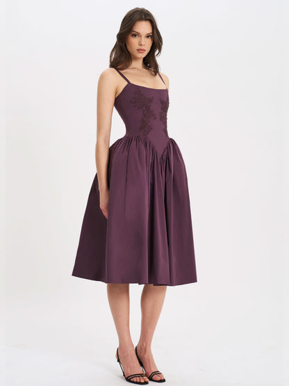 Purple midi dress with spaghetti straps and flowing skirt hem showing wedding guest style