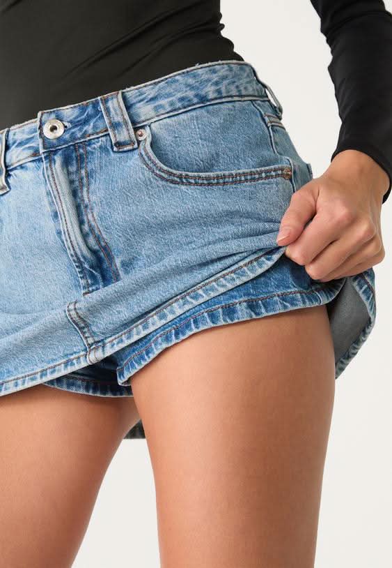 Close-up of denim skort waistband and front pocket detail in light blue wash