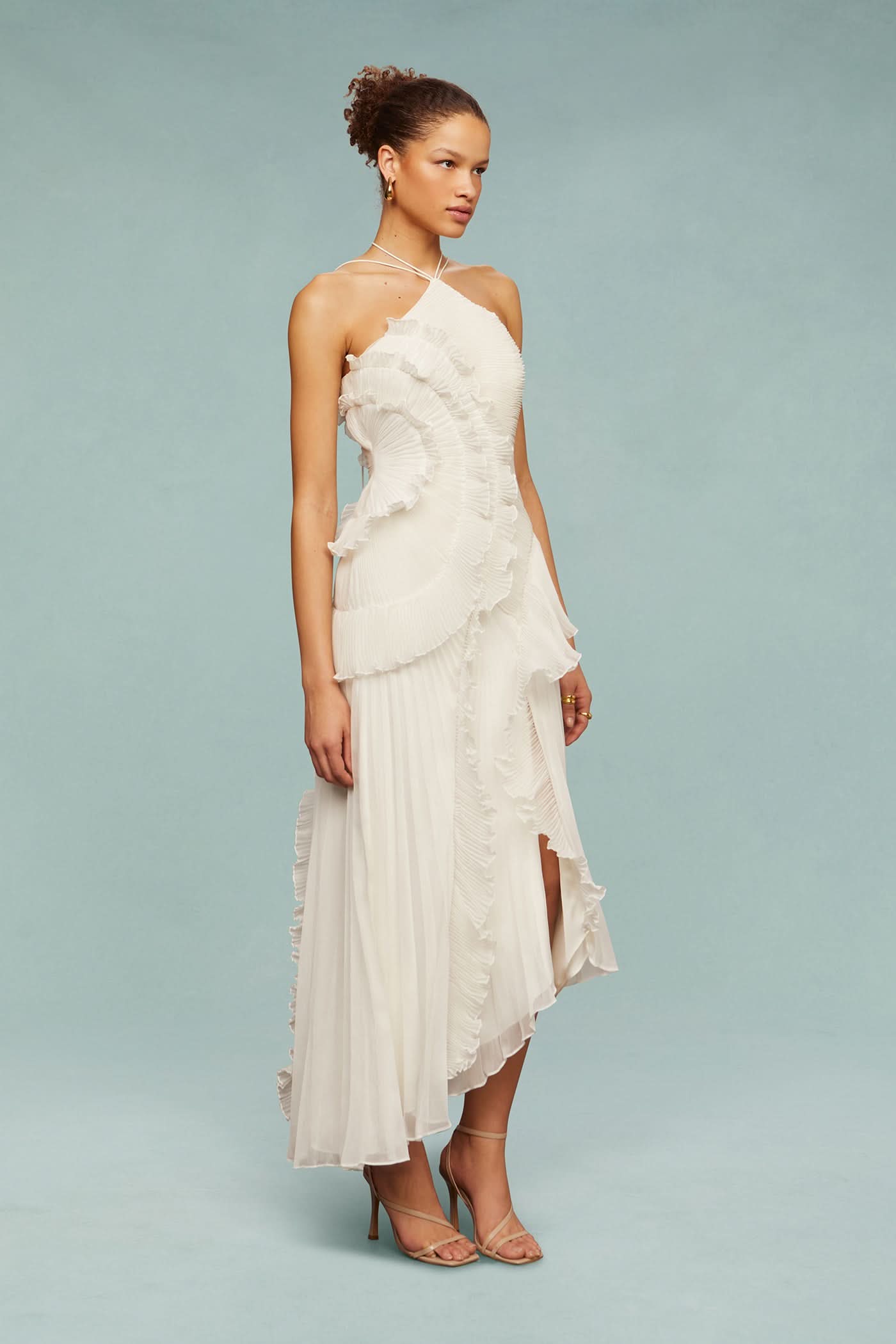 Side profile of cream halter dress with layered ruffle design