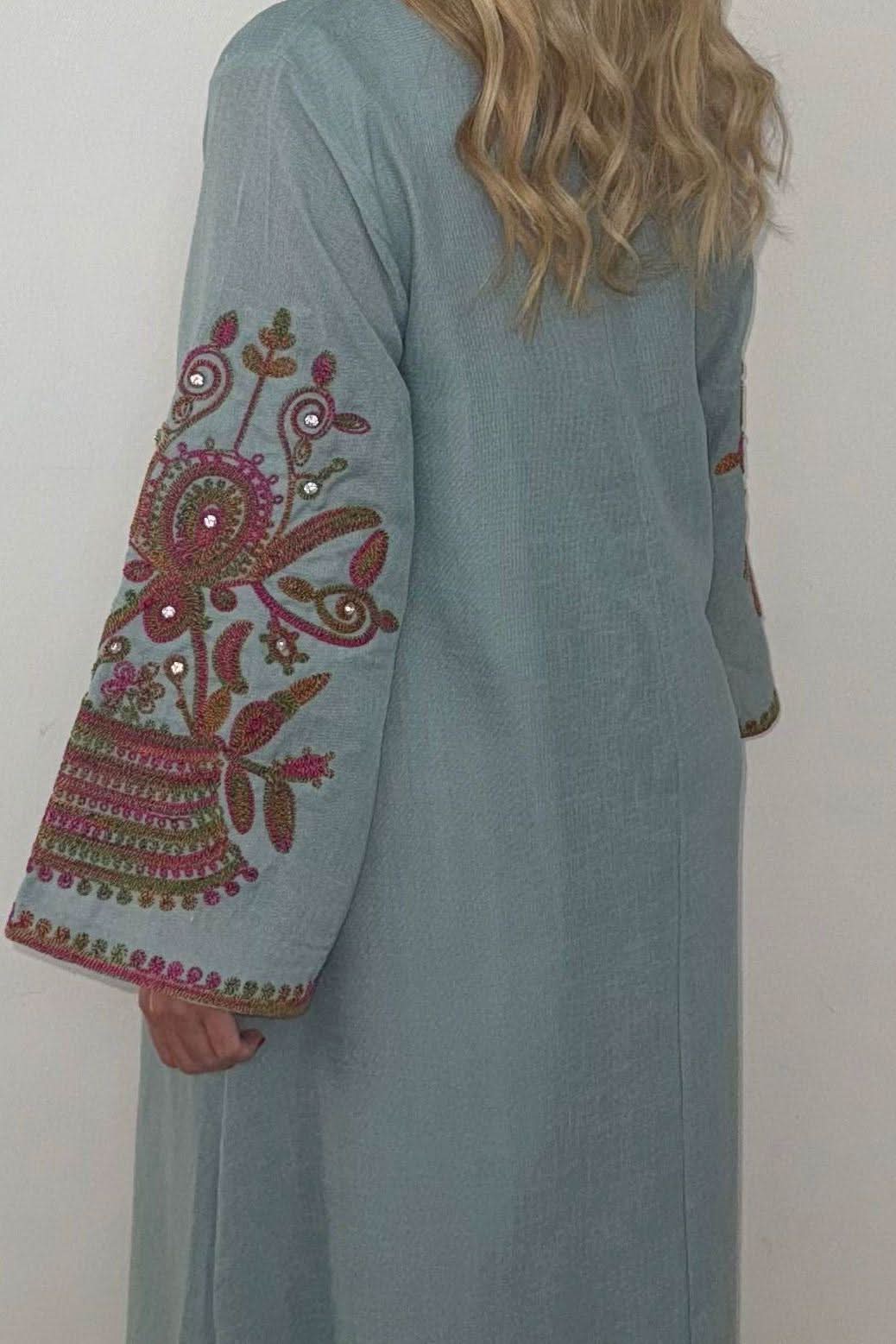 Close-up of sage green kaftan sleeve showing burgundy floral embroidery