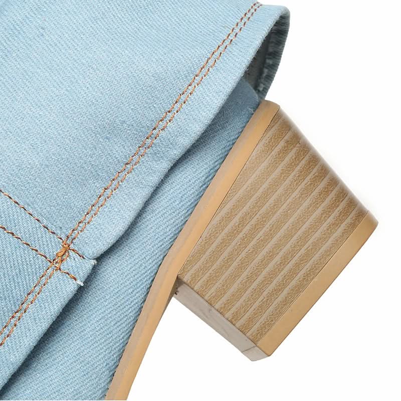 Close-up detail of light blue denim boot fabric with orange stitching and wooden heel