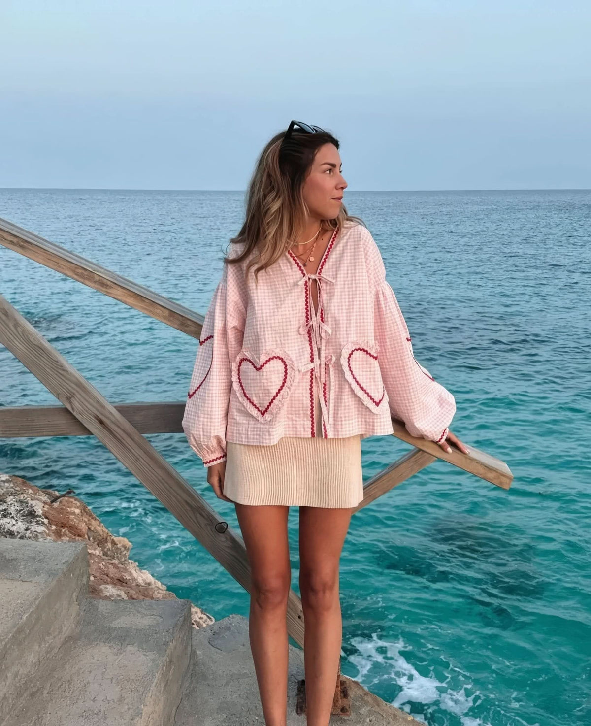 Pink gingham heart top styled with cream ribbed skirt at coastal setting