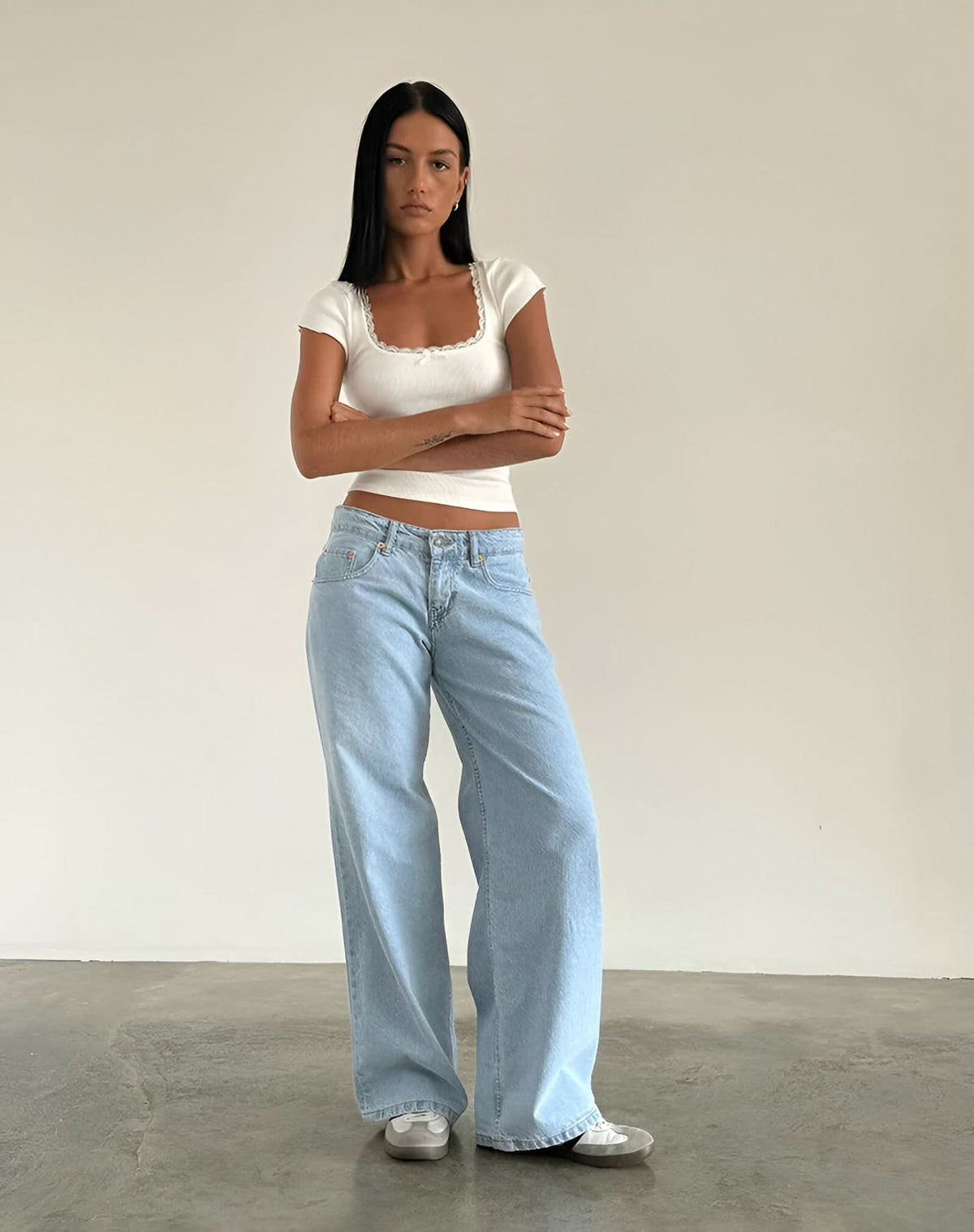 Light wash low-rise jeans with white lace-trim cap sleeve crop top