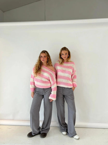 Pink and cream striped knit sweater on two models with gray trousers