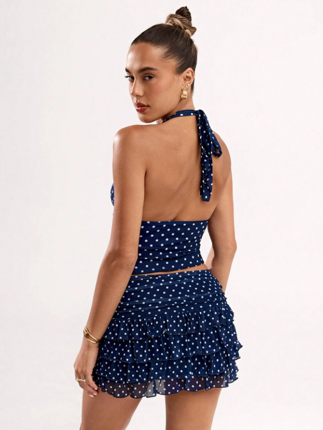 Open back halter tie detail on navy polka dot crop top with layered ruffle mini skirt