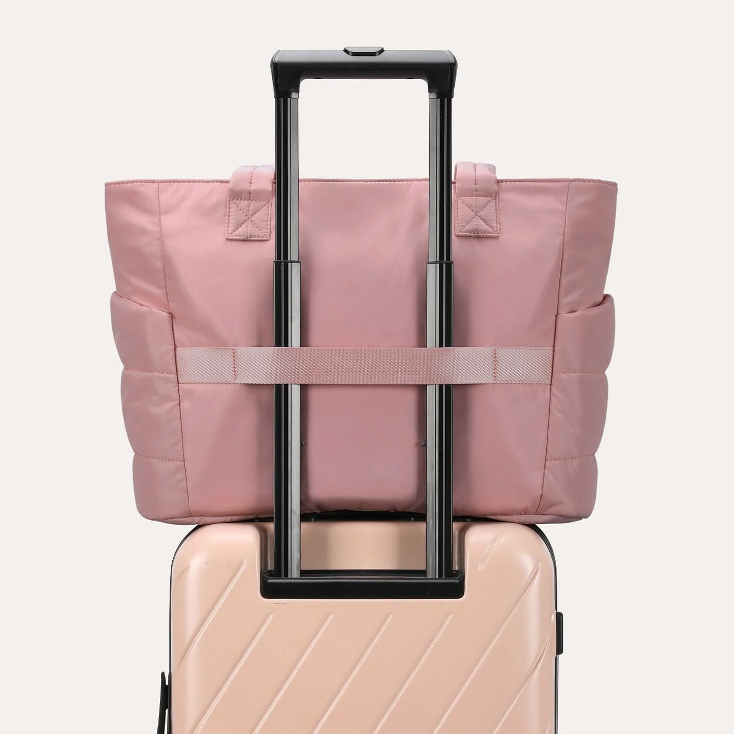 Pink quilted tote attached to luggage handle with adjustable straps