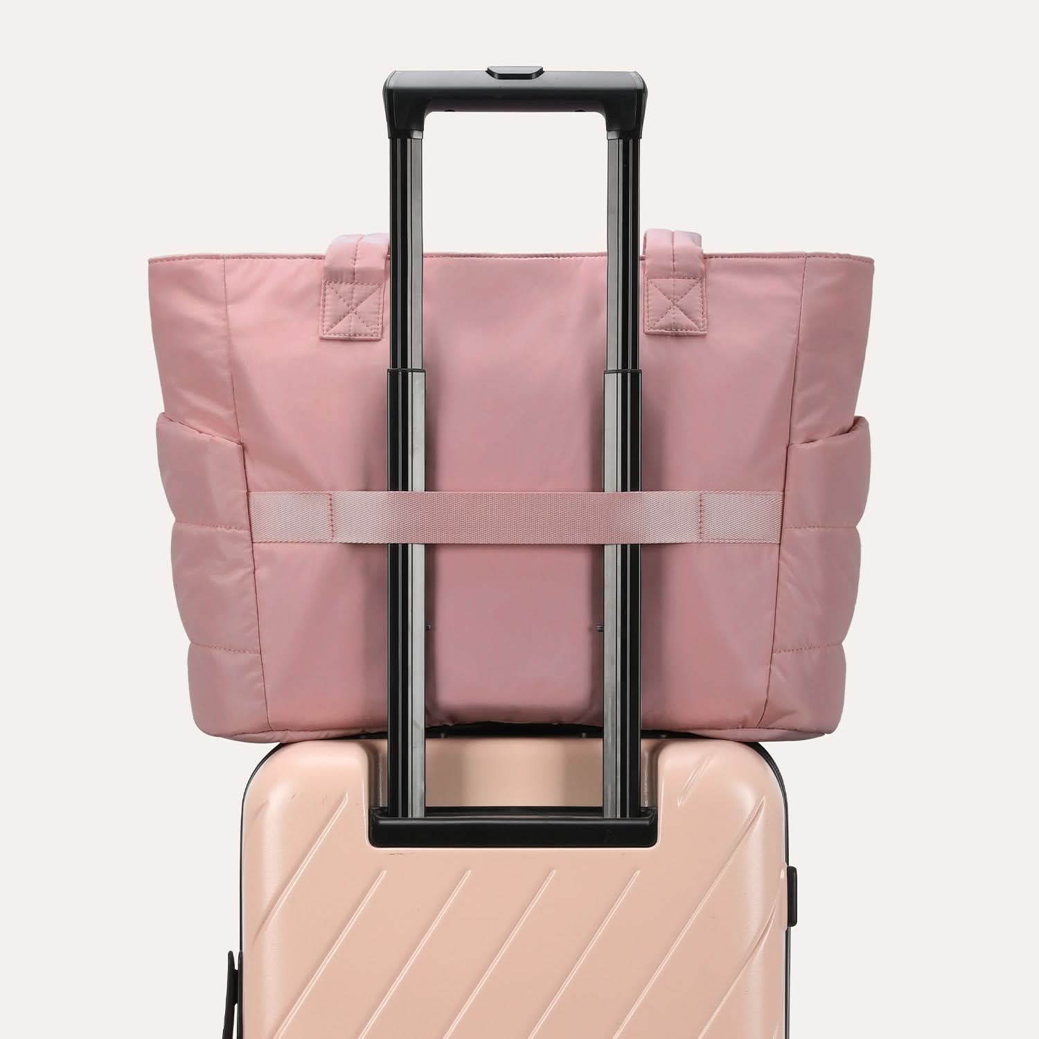 Pink quilted tote attached to luggage handle with adjustable straps