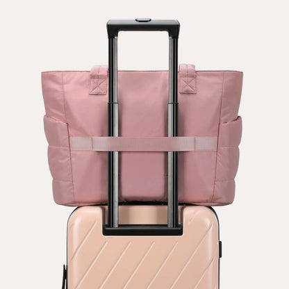 Pink quilted tote attached to luggage handle with adjustable straps