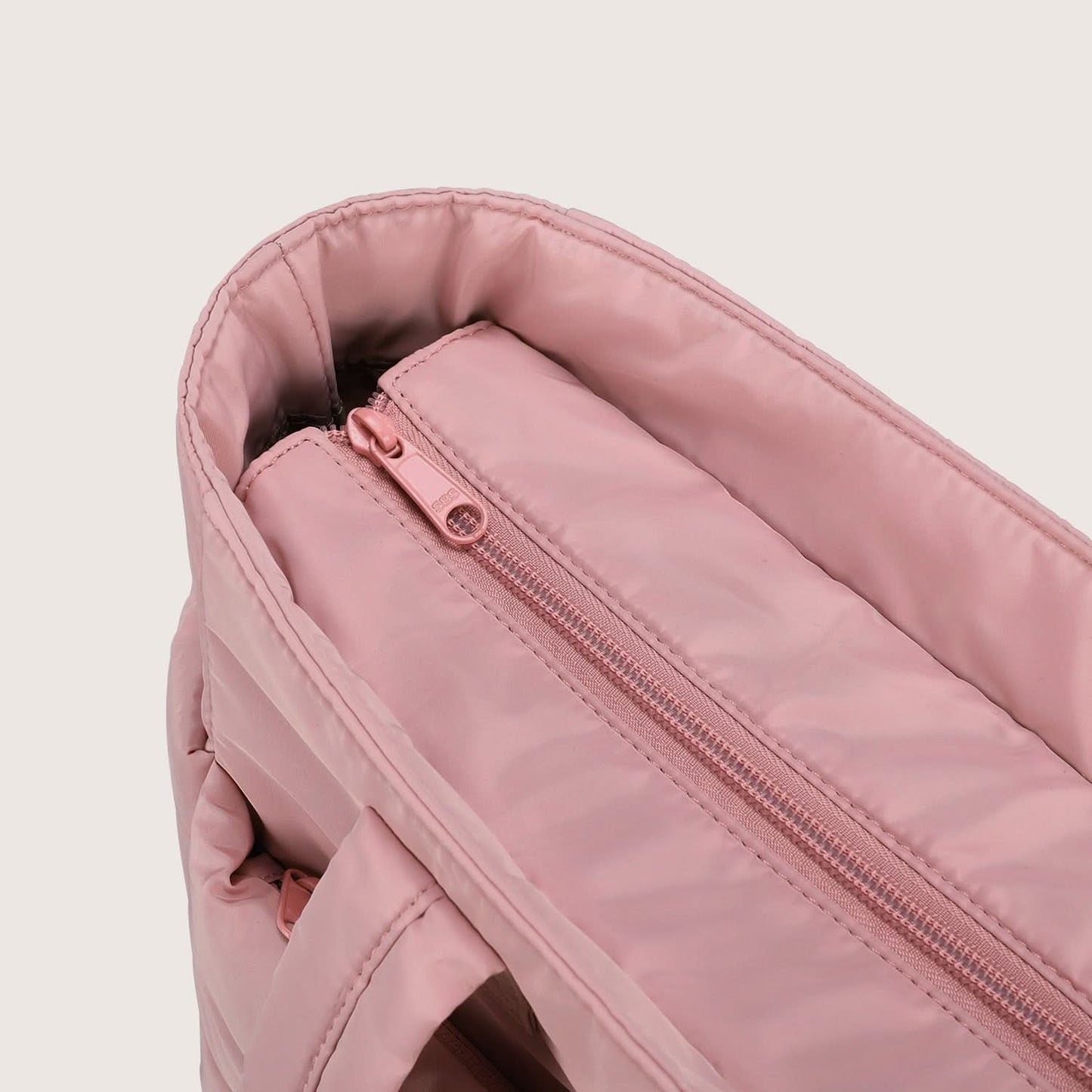 Close-up of pink quilted tote fabric with water droplets beading on surface