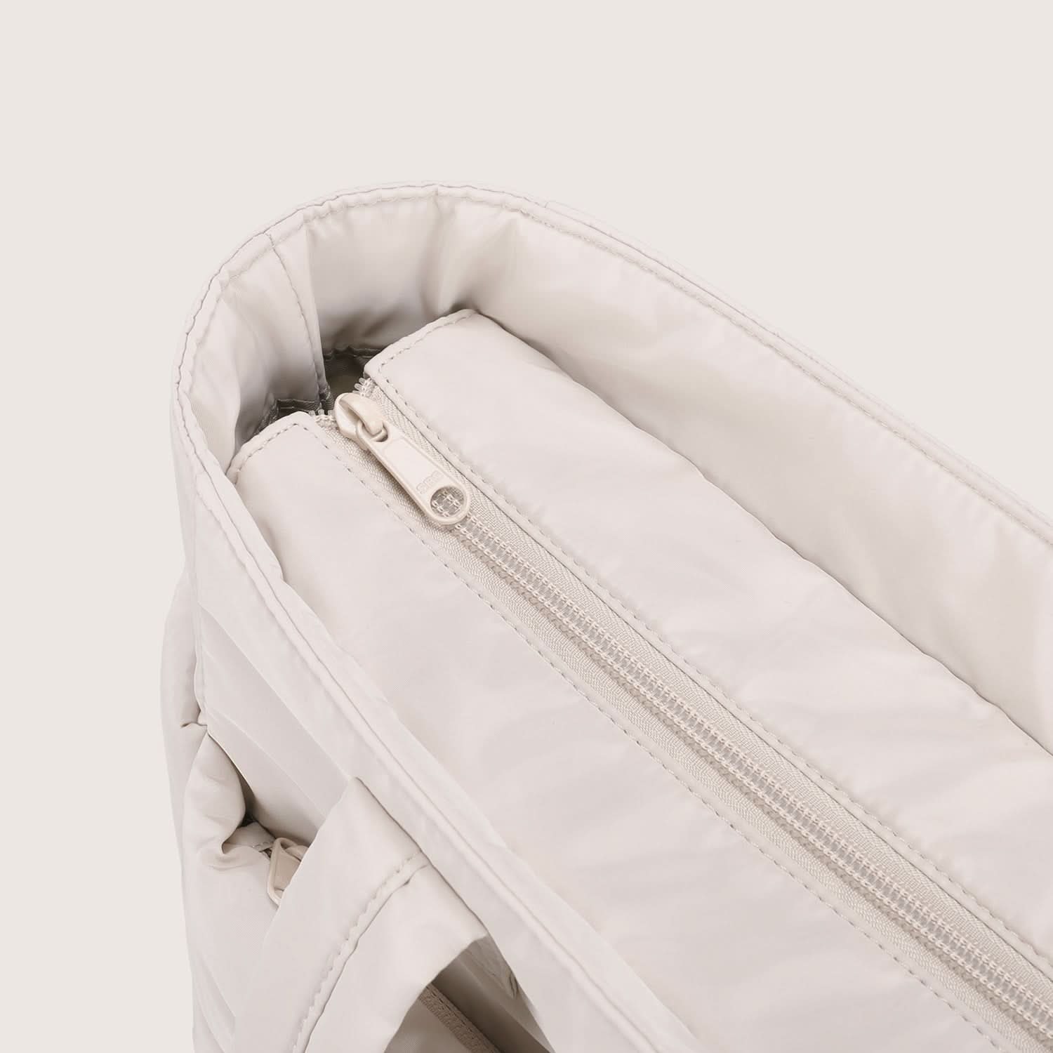 Close-up of cream tote interior zipper pocket with soft lining detail