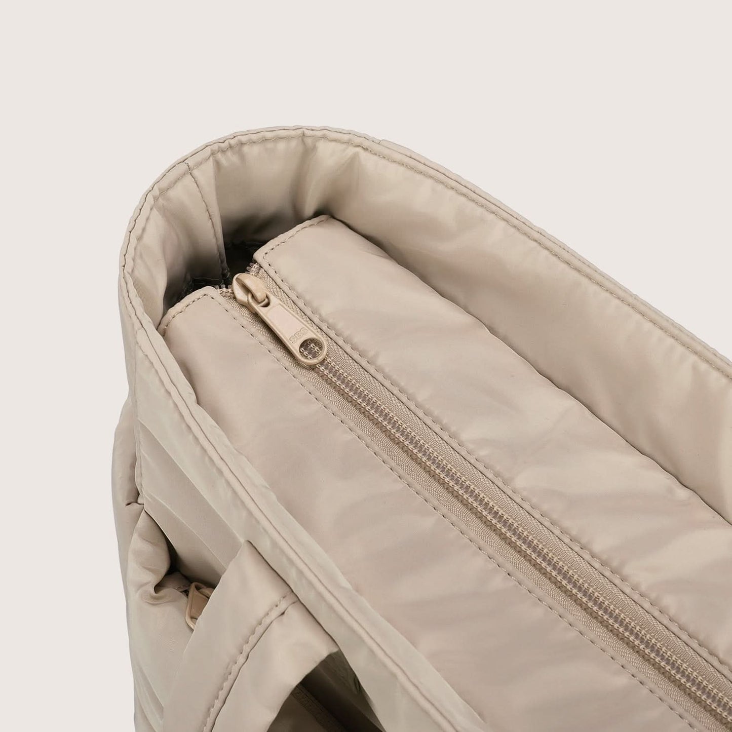 Close-up of beige tote interior zip pocket with metal slider detail