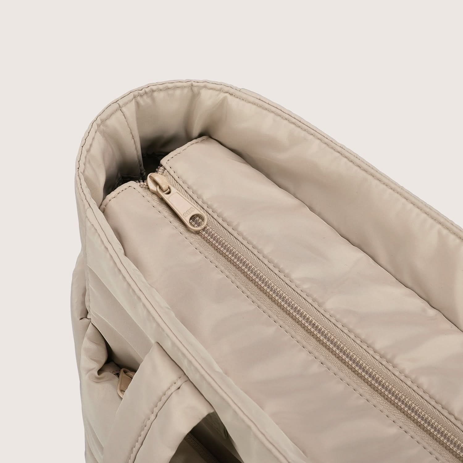 Close-up of beige tote interior zip pocket with metal slider detail