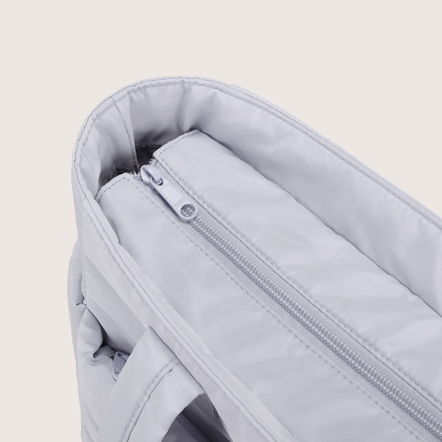 Close-up of light gray tote interior zip pocket with metal slider