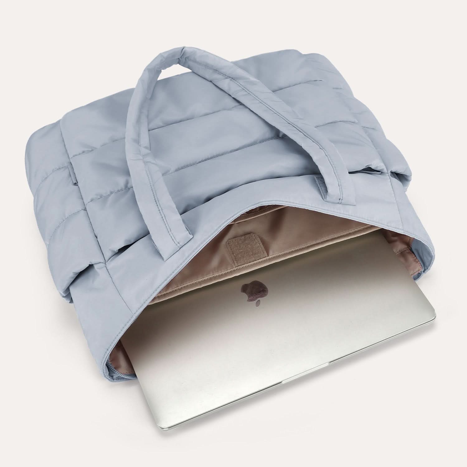 Light blue quilted tote with padded handles holding open laptop compartment