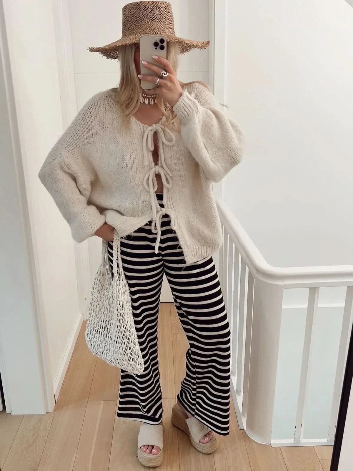 Cream knit cardigan with front bow ties and puffed sleeves, styled with striped pants
