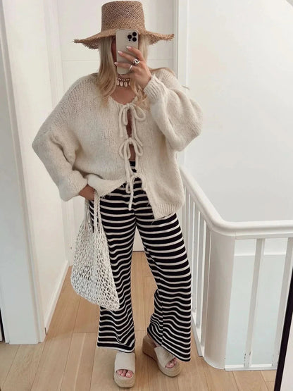 Cream knit cardigan with front bow ties and puffed sleeves, styled with striped pants