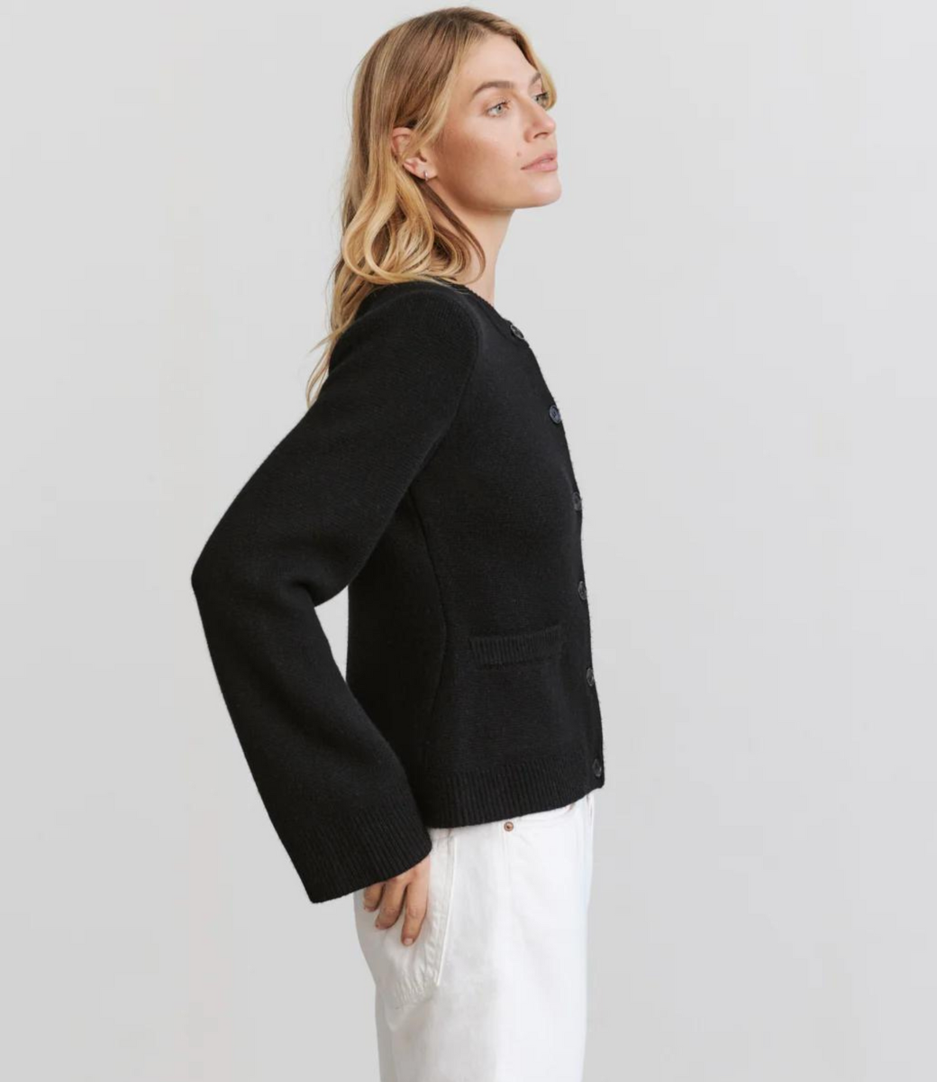 Black button cardigan with ribbed trim, side profile showing relaxed fit and long sleeves