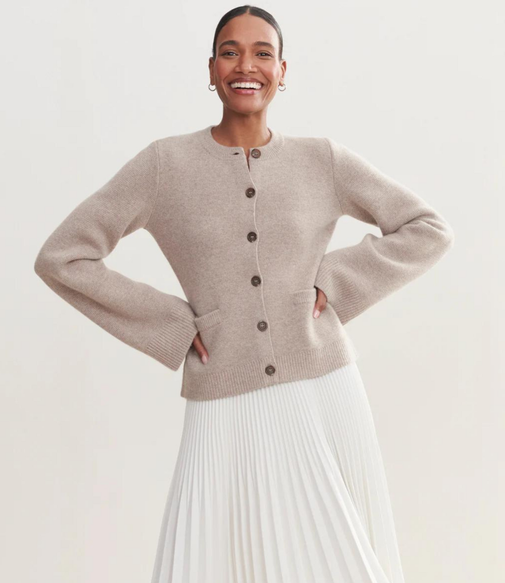 Black button cardigan with crew neckline and ribbed details, front view with white pants