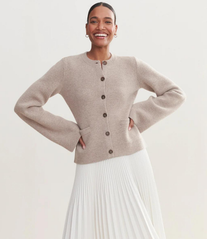 Black button cardigan with crew neckline and ribbed details, front view with white pants