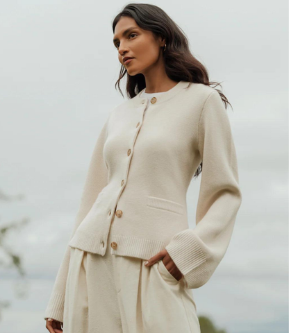 Cream button-front cardigan with ribbed cuffs and waist detail, worn with matching pleated skirt