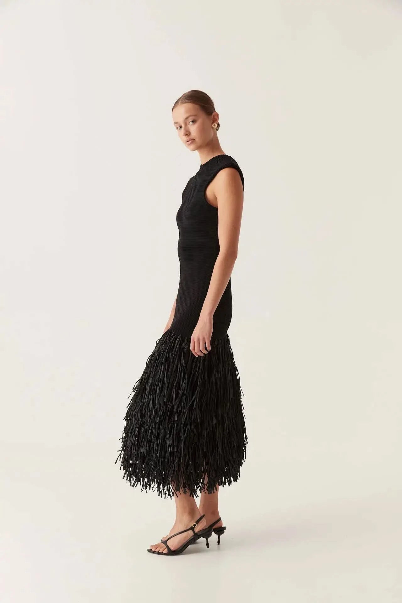 Side view of black midi knit dress showing fitted silhouette and layered fringe