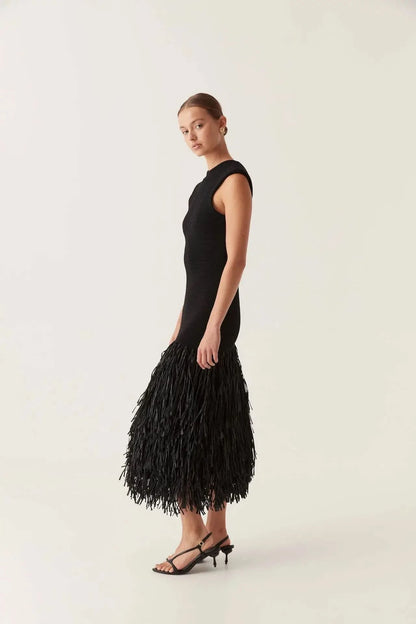 Side view of black midi knit dress showing fitted silhouette and layered fringe