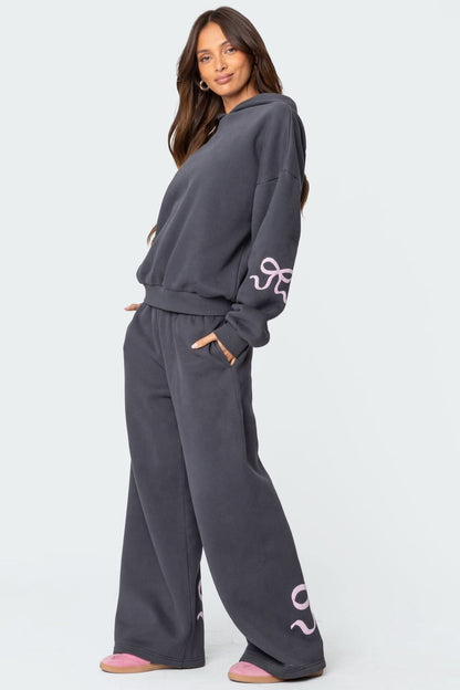 Side view of charcoal gray bow hoodie with pink graphic embroidery on sleeves