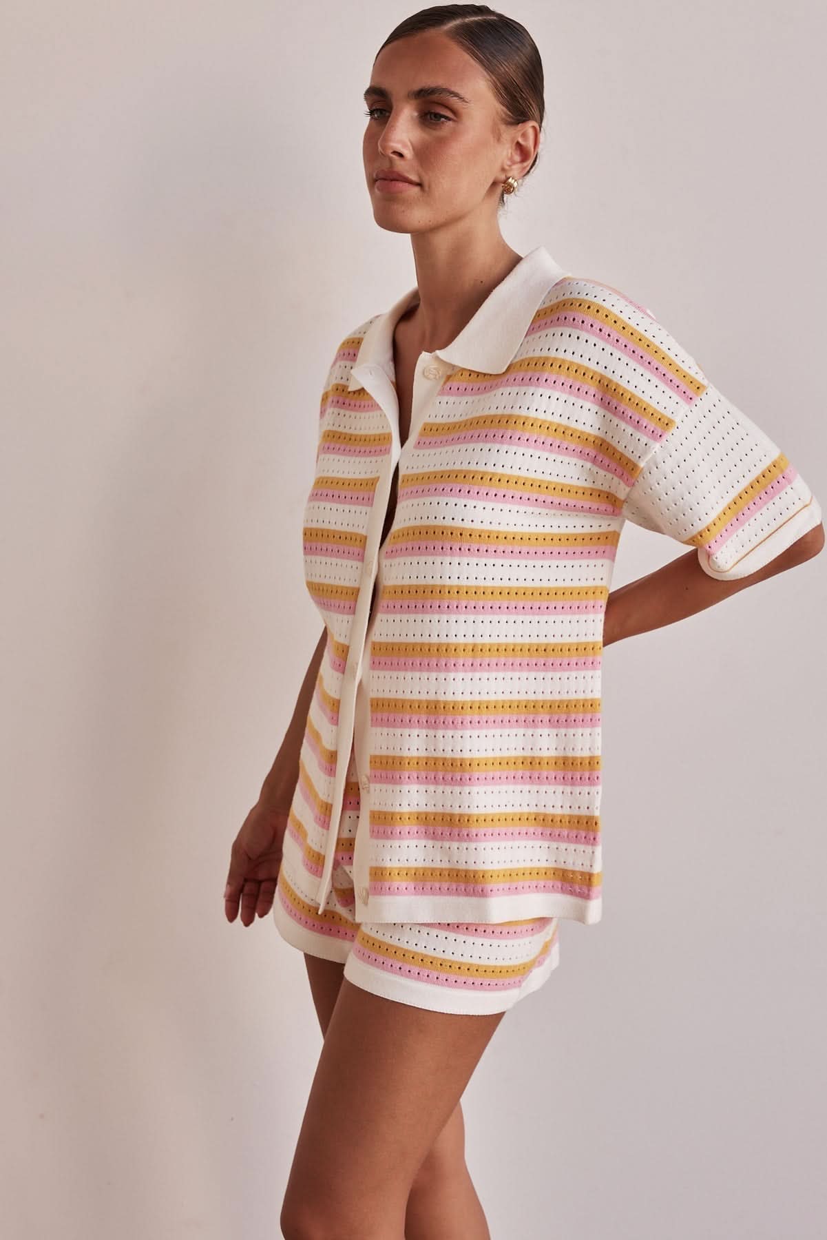 Striped pointelle knit collared top with short sleeves shown on model from side angle