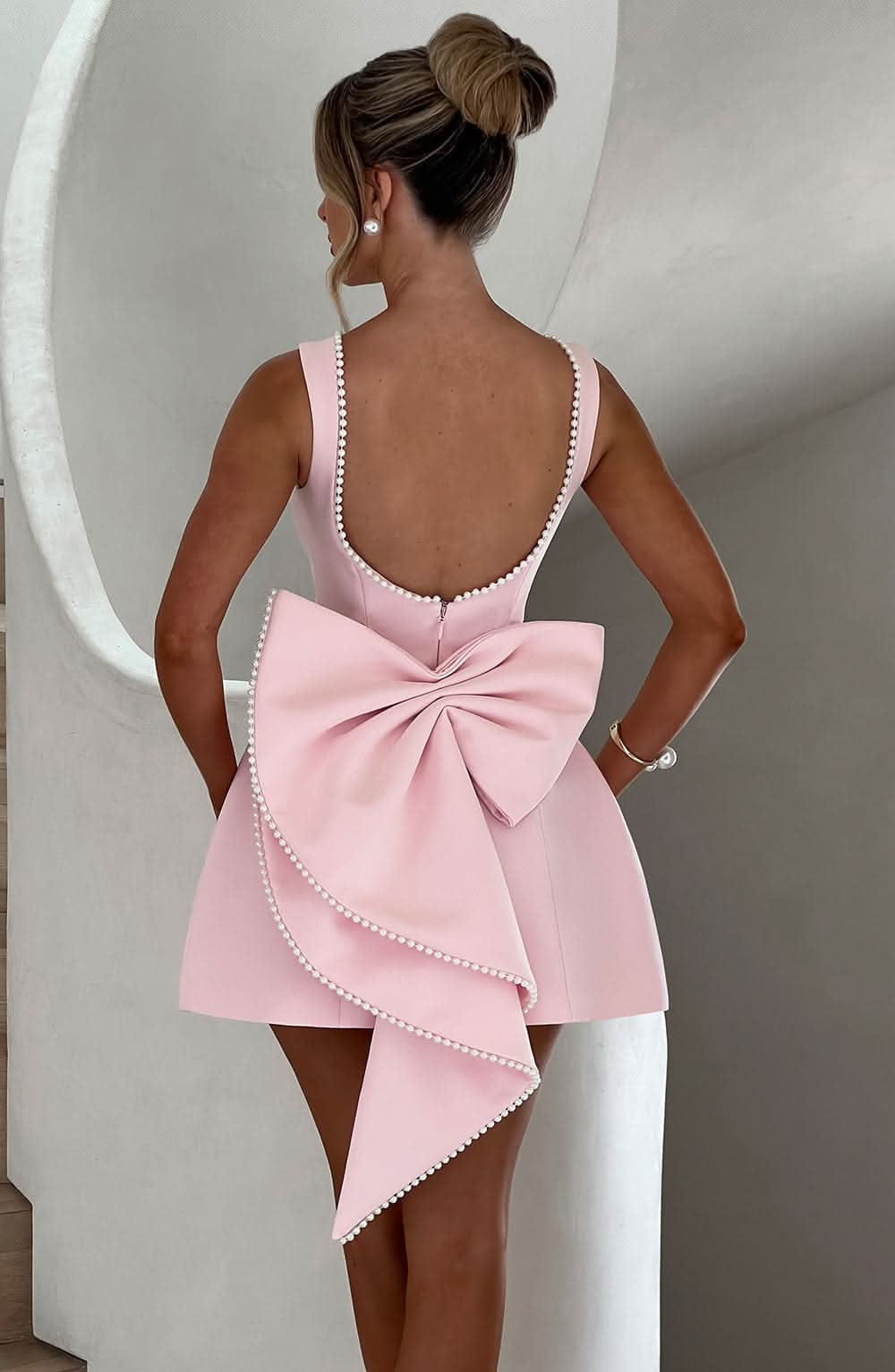 Black mini dress back view with pearl-beaded scoop back and asymmetrical bow