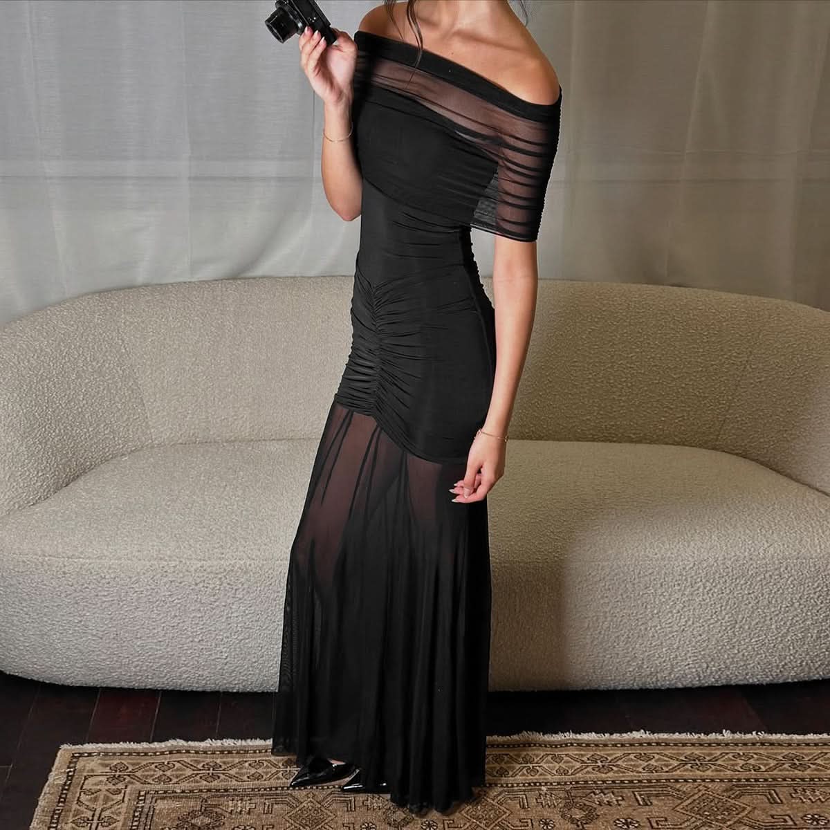 Black off-shoulder maxi dress side view showing ruched bodice and transparent hem