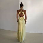 Back view of pale yellow maxi dress with open back and tied bow accent at waist