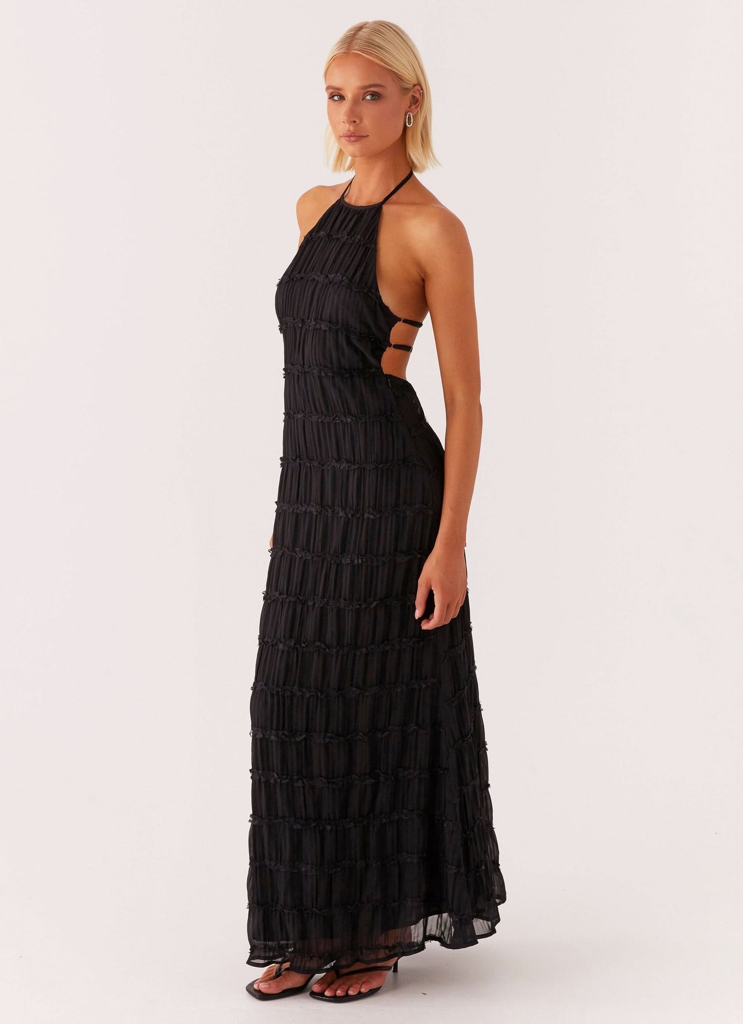 Side view of black halter maxi dress with side cutout straps