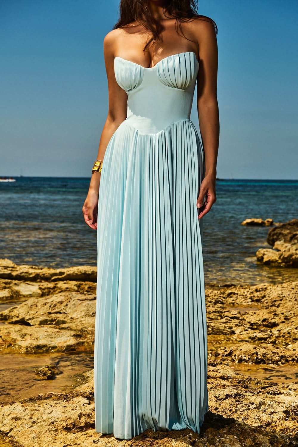 Light blue pleated strapless maxi dress worn at beach with ocean backdrop