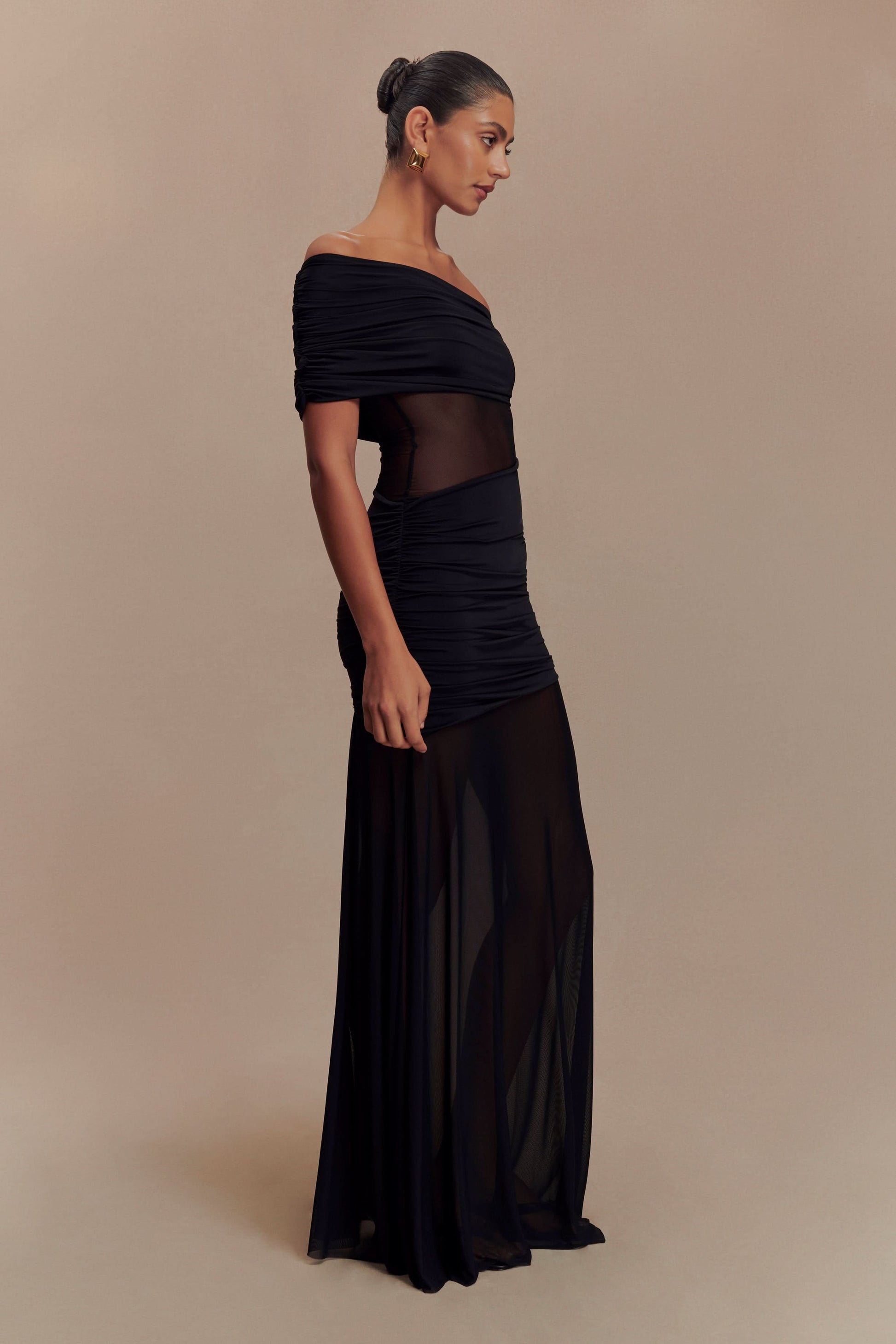 Side profile of black off-shoulder maxi dress with sheer cutout waist