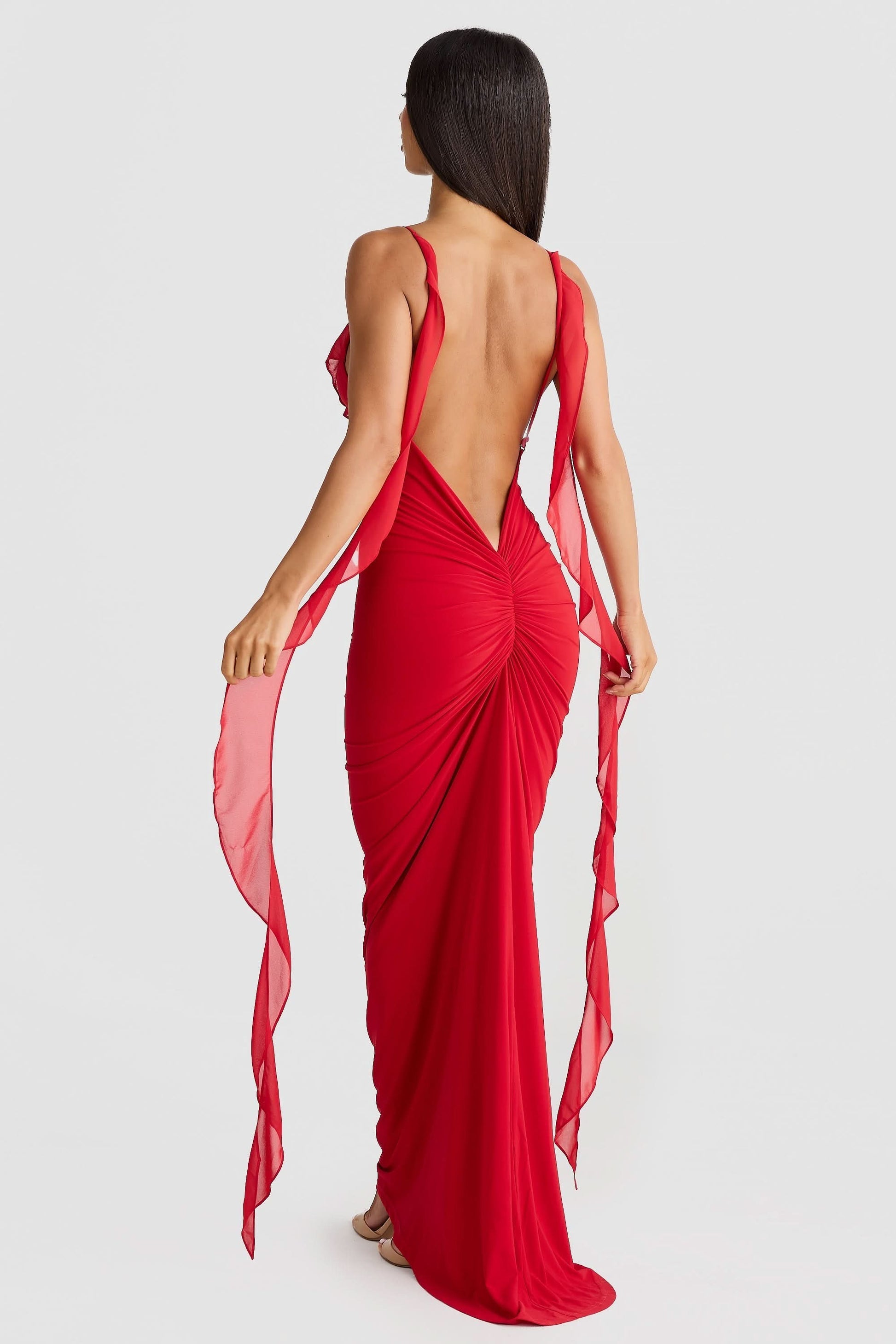 Red maxi dress back view featuring open back design with ruched detailing and flowing fabric