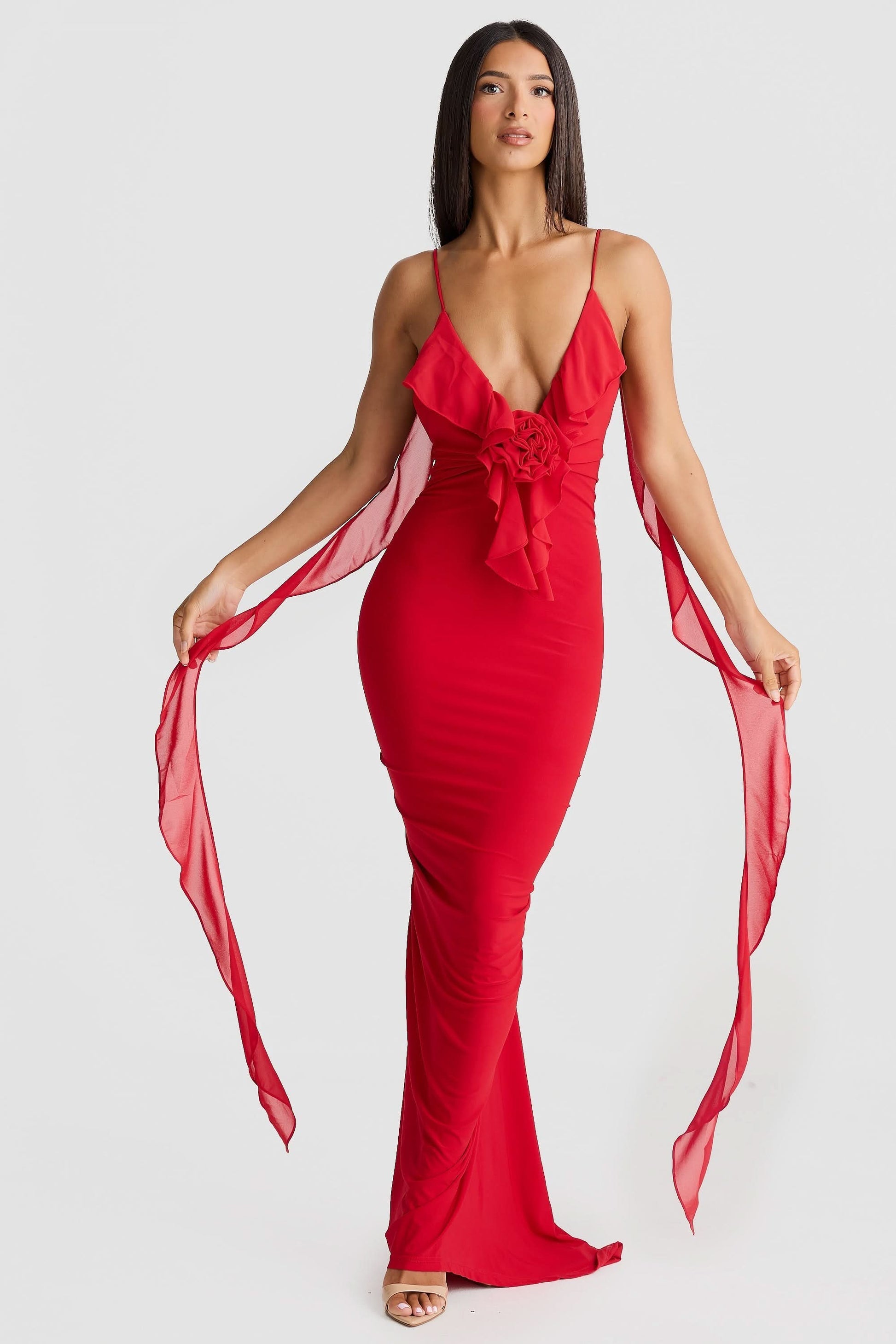 Red wrap maxi dress front view with ruffled V-neckline, cinched waist, and sheer trailing panels