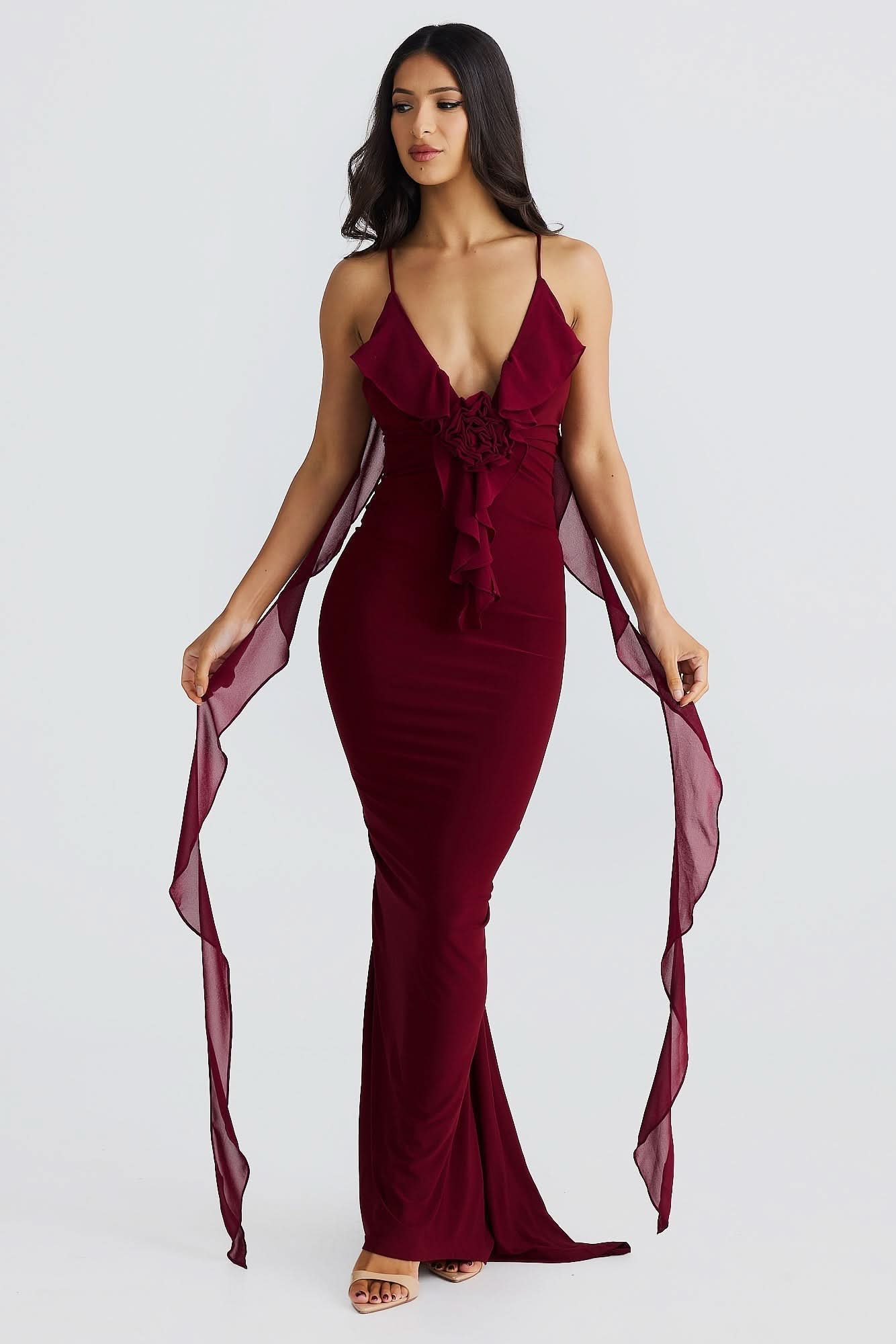 Burgundy maxi dress front view with ruffled V-neckline, decorative waist tie, and sheer side panels