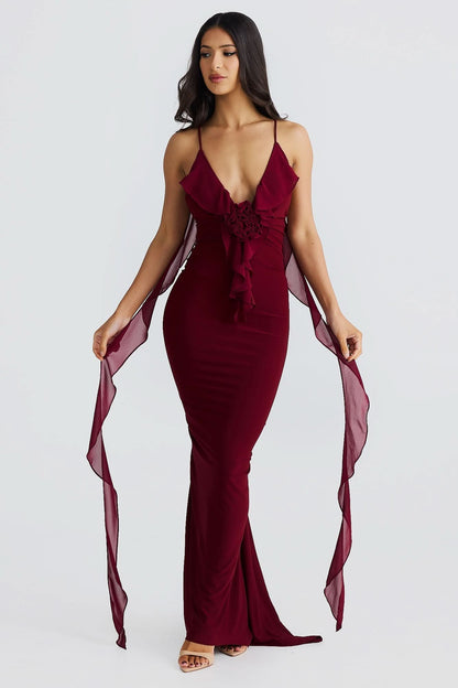 Burgundy maxi dress front view with ruffled V-neckline, decorative waist tie, and sheer side panels