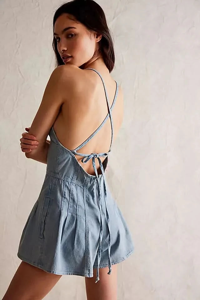 Back view of light wash denim romper showing lace-up tie detail and pleated shorts