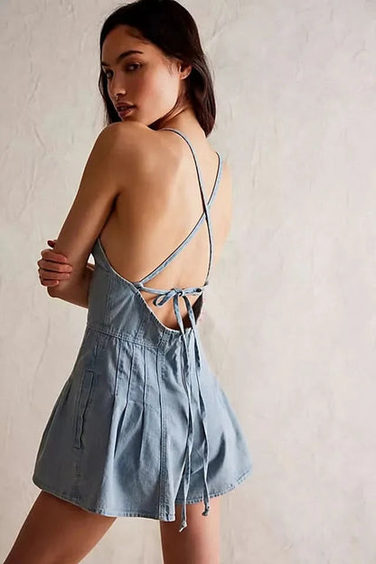 Back view of light wash denim romper showing lace-up tie detail and pleated shorts
